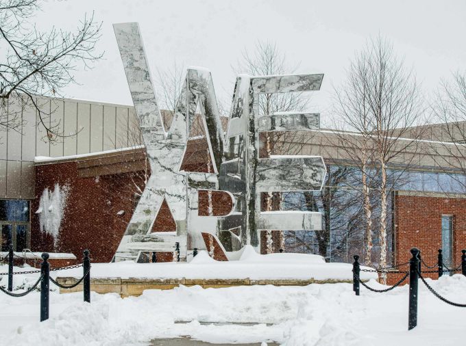 "We Are" mirrored surface sculpture with snow on the ground.